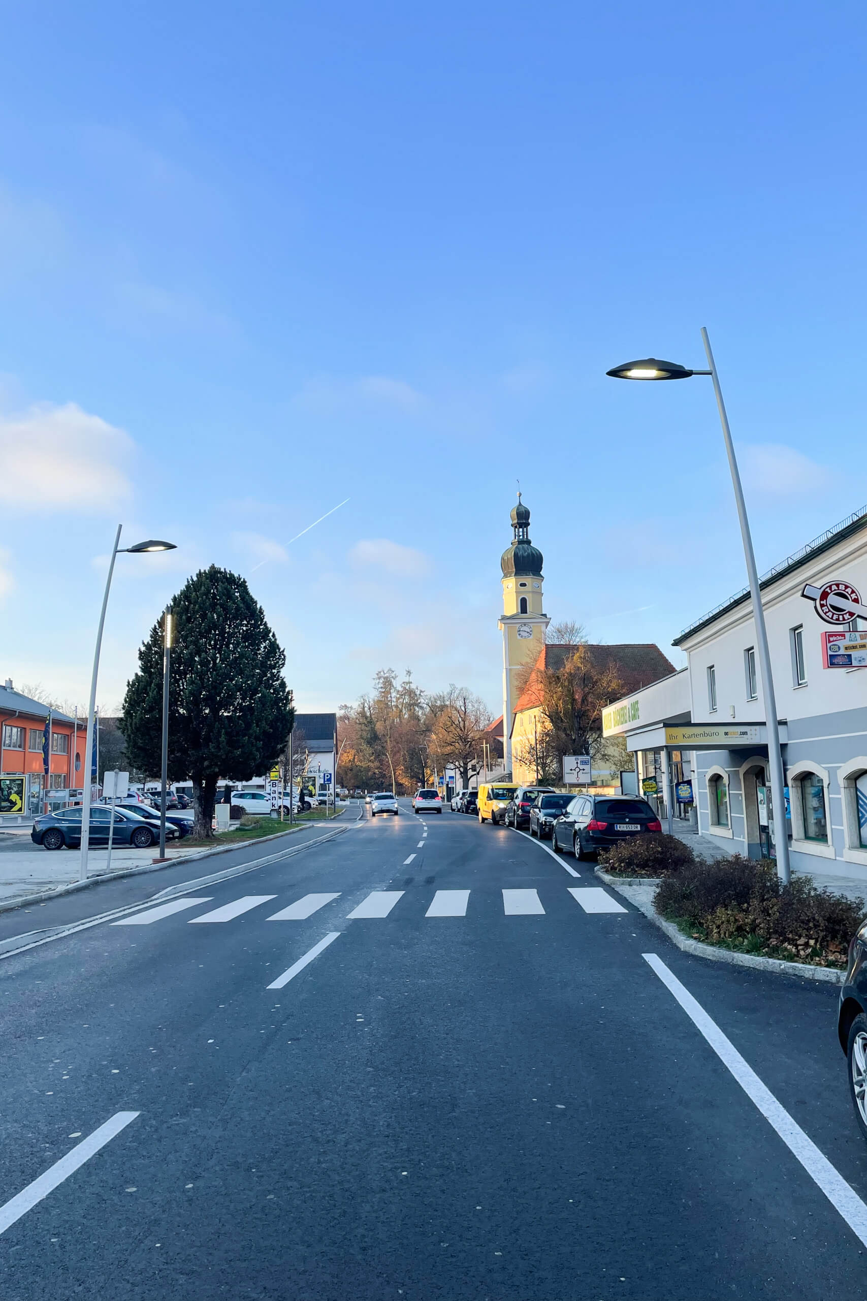 Straßenbeleuchtung im Ortskern mit Kirche und Geschäften – Lichtplanung von Illumina.
