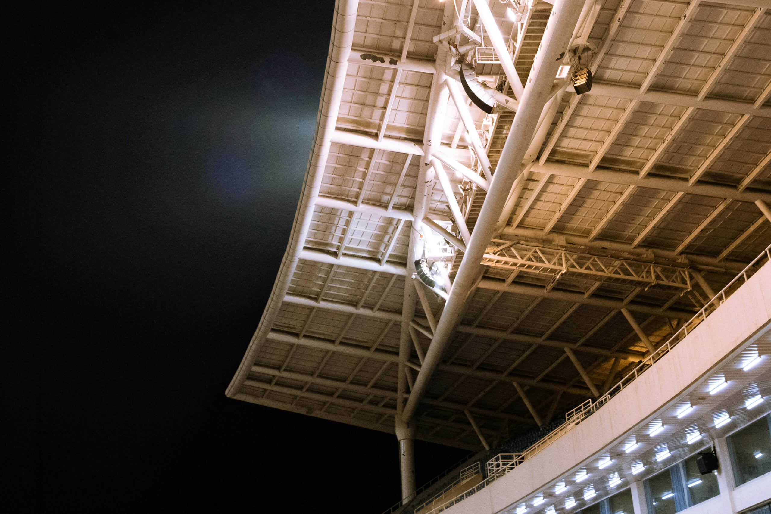 Moderne Sportplatzbeleuchtung mit Stahlkonstruktion und Lichtträgern bei Nacht.