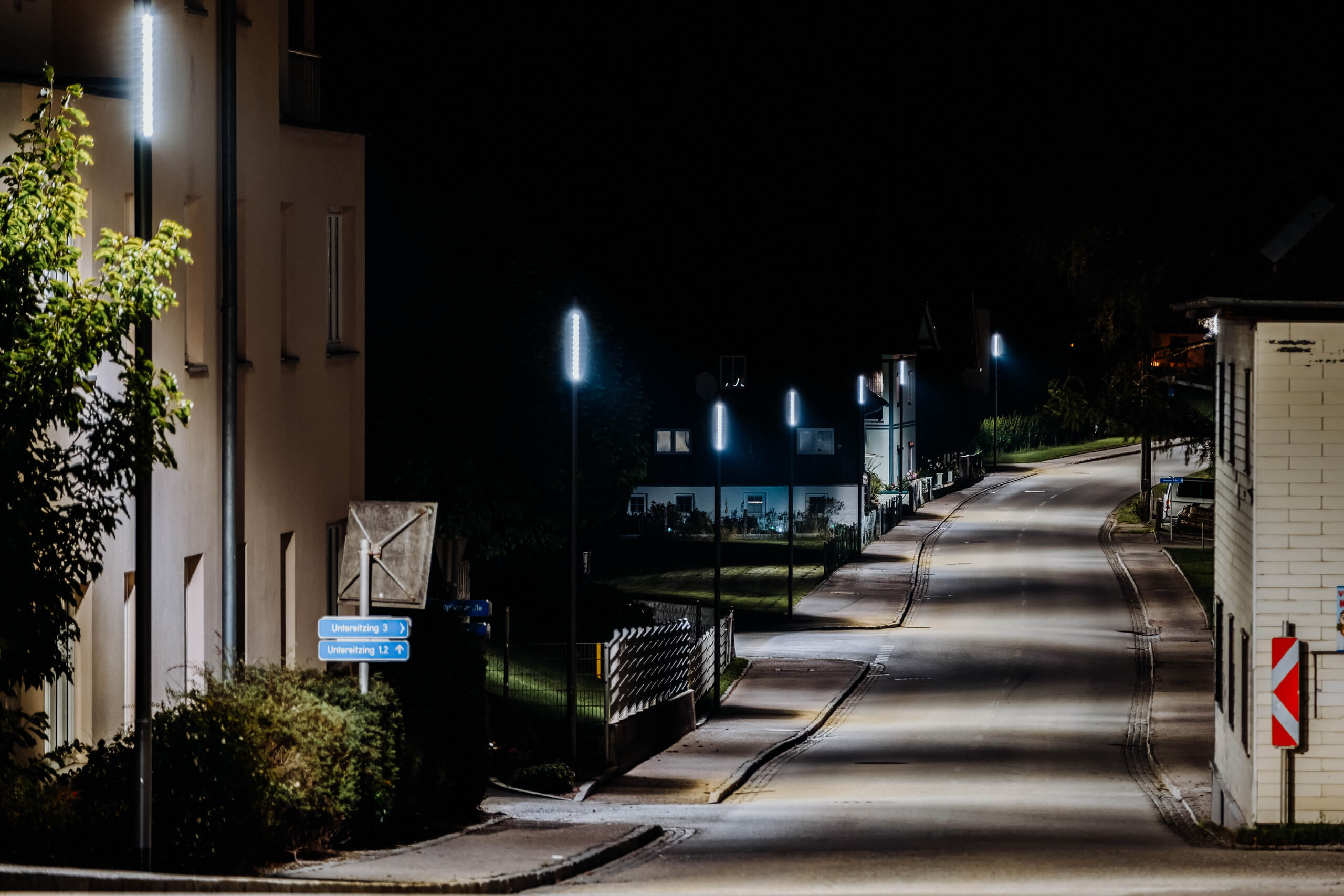 Straßenbeleuchtung beleuchtet eine dunkle Straße mit modernen Laternen und Gebäuden.