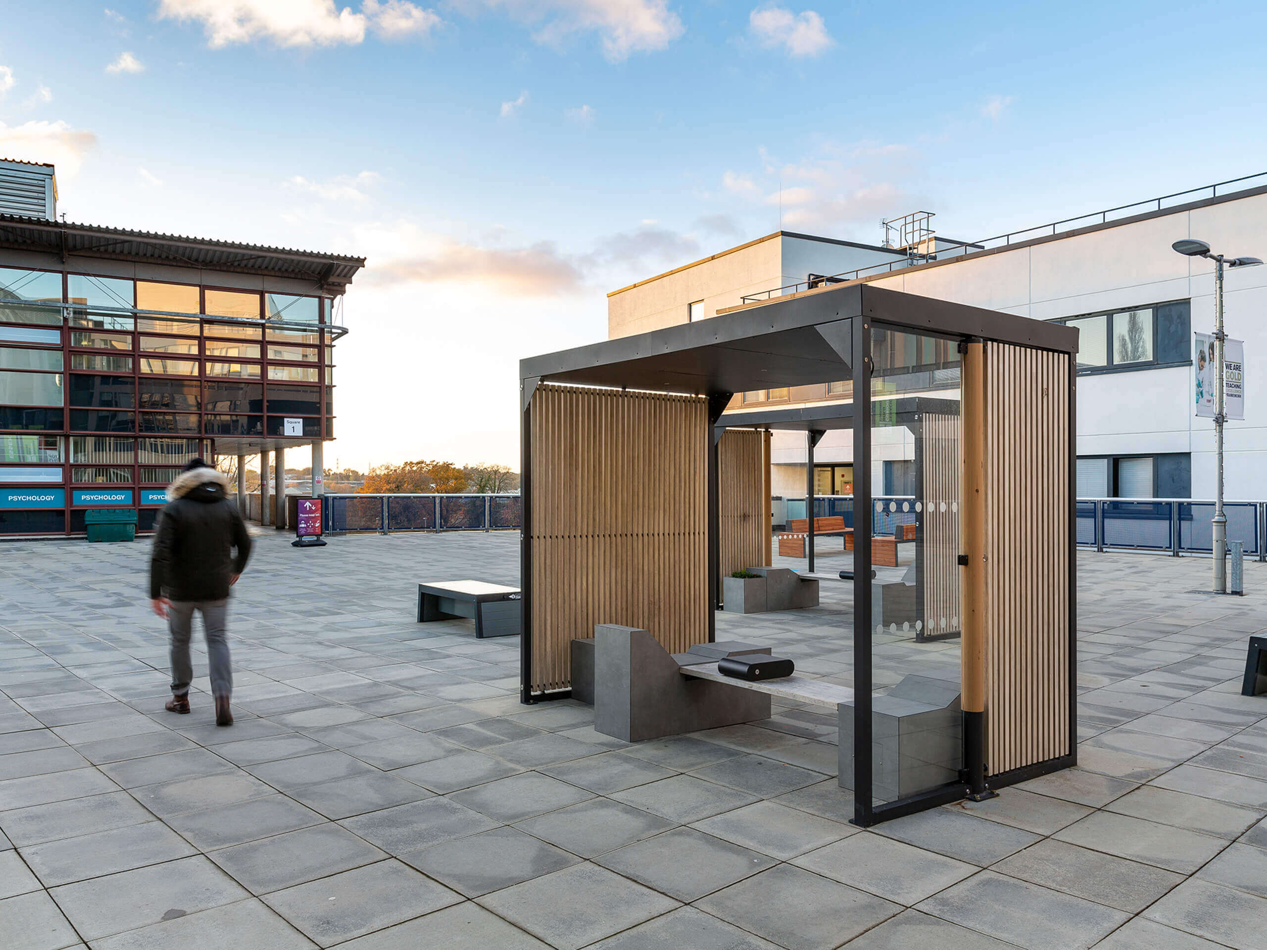 Modernes Stadtmobiliar mit Sitzgelegenheiten und Holzelementen auf einem Platz.