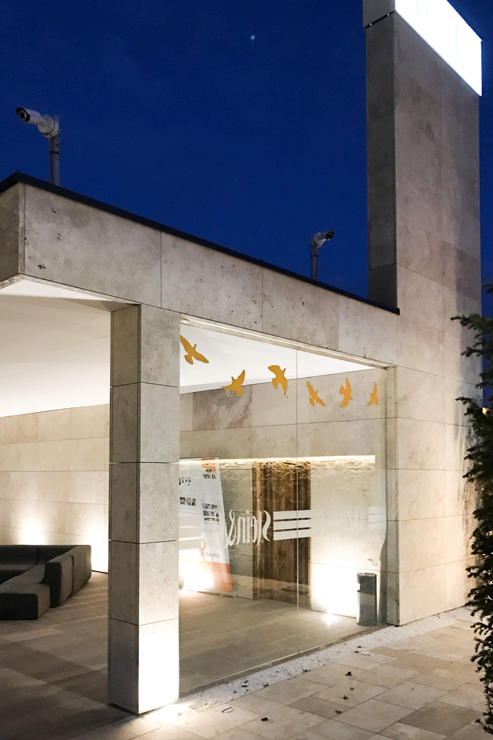 Illumina Lichtplanung: Fassade eines modernen Gebäudes mit Vogel-Dekorationen am Abend