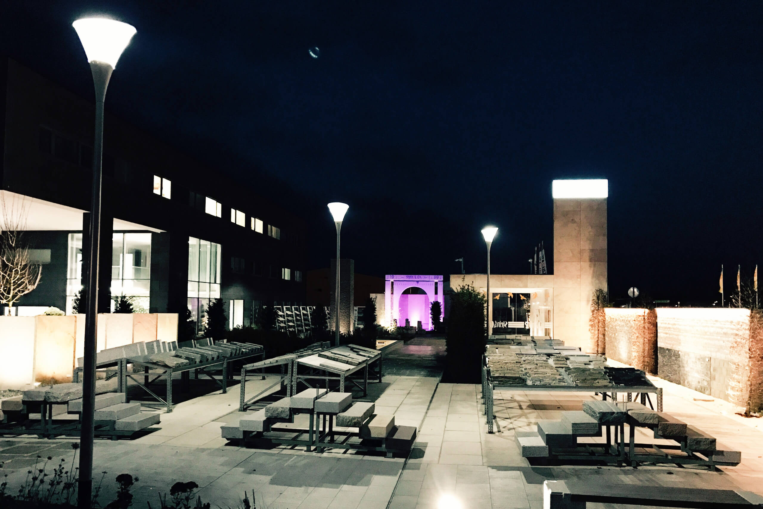 Beleuchtete Außenanlage mit Sitzgelegenheiten und moderner Architektur bei Nacht