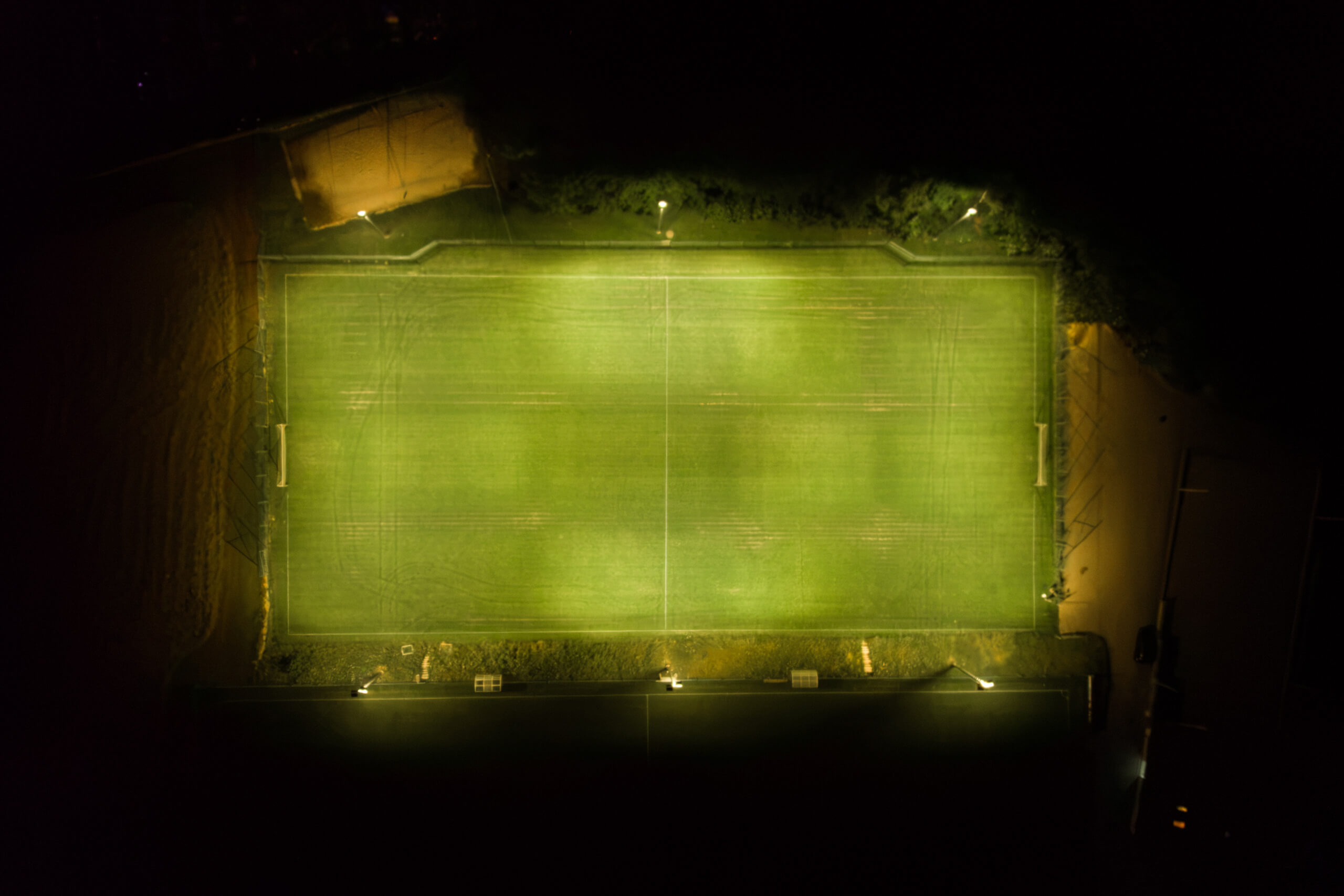 Beleuchteter Fußballplatz bei Nacht mit Flutlichtstrahlern von Illumina