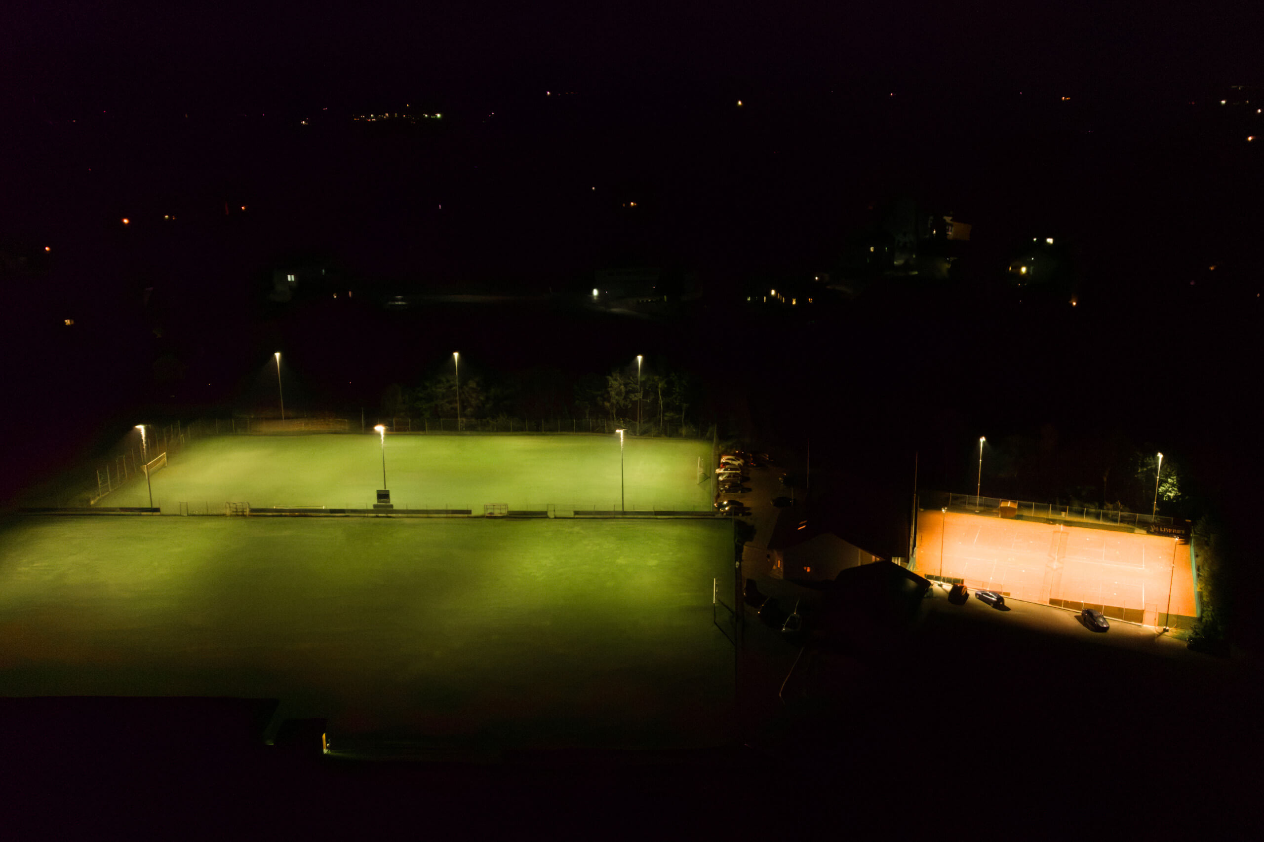 Beleuchtete Sportplätze bei Nacht, Tennisplatz und Fußballfeld, Lichtplanung von Illumina.