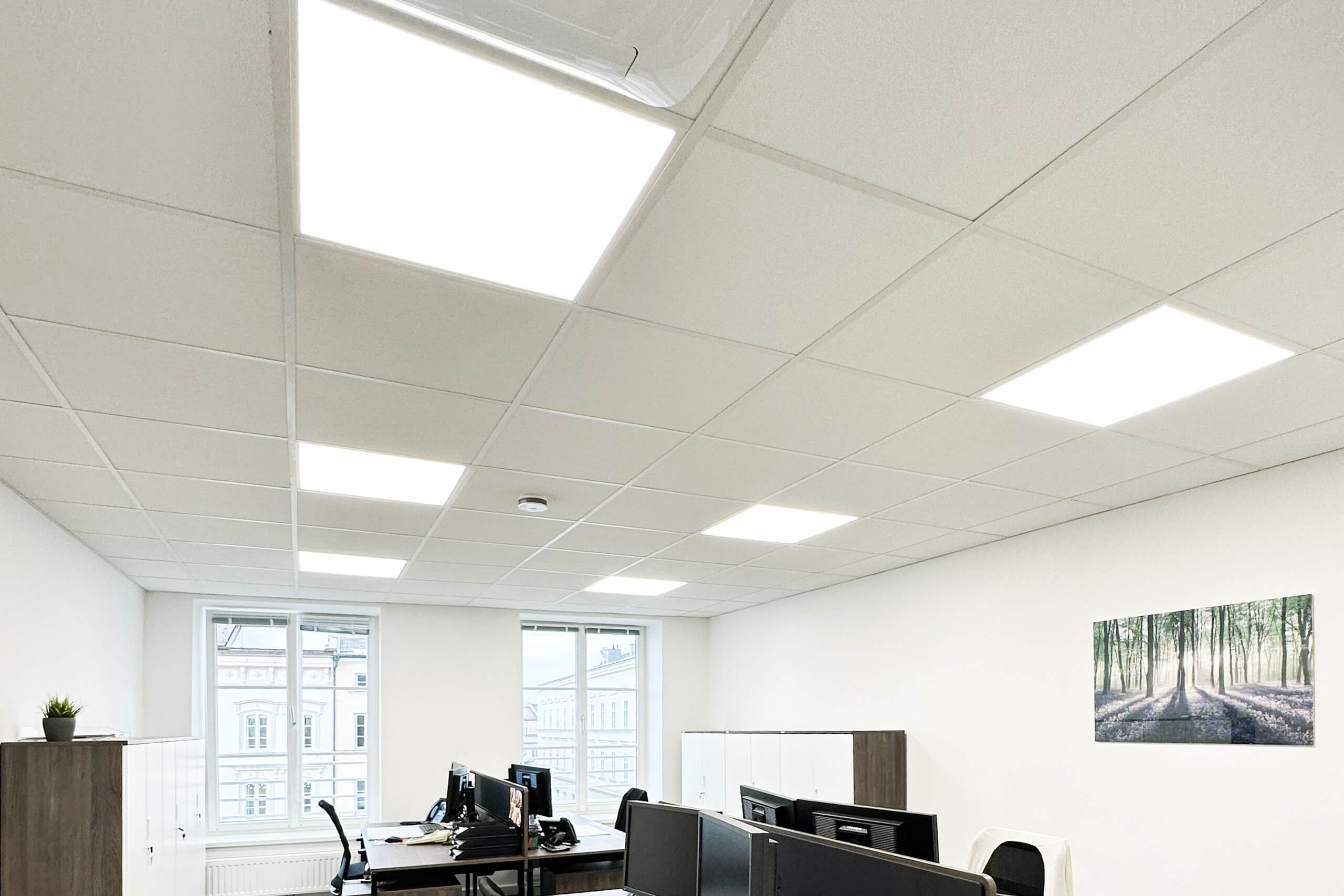 Helles Büro mit moderner Deckenbeleuchtung und großen Fenstern