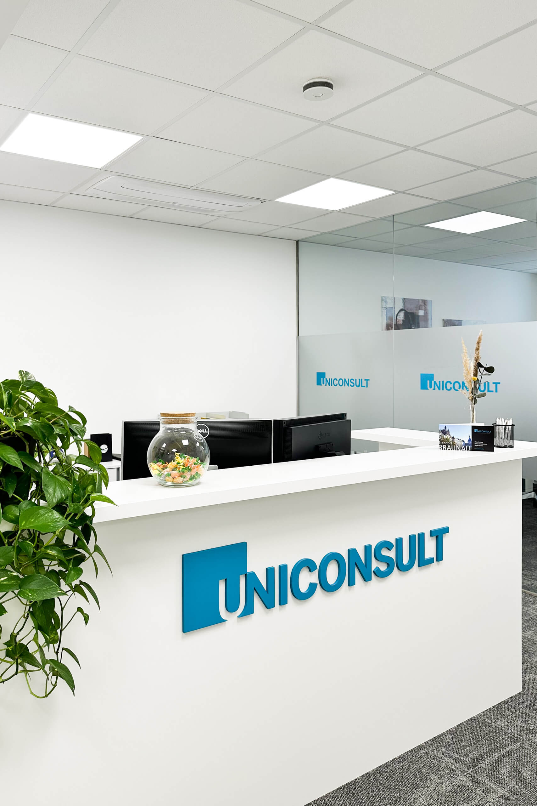 Moderne Empfangshalle mit dem Logo UNICONSULT und Pflanzen