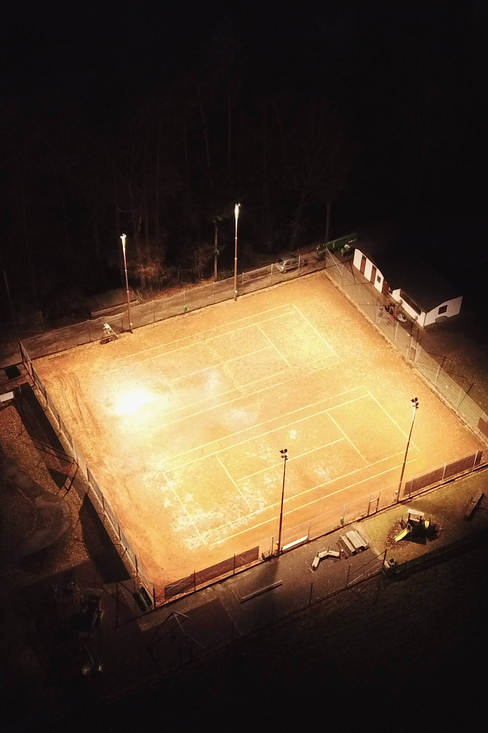 Sportplatzbeleuchtung bei Nacht mit hellen Flutlichtern und markiertem Spielfeld