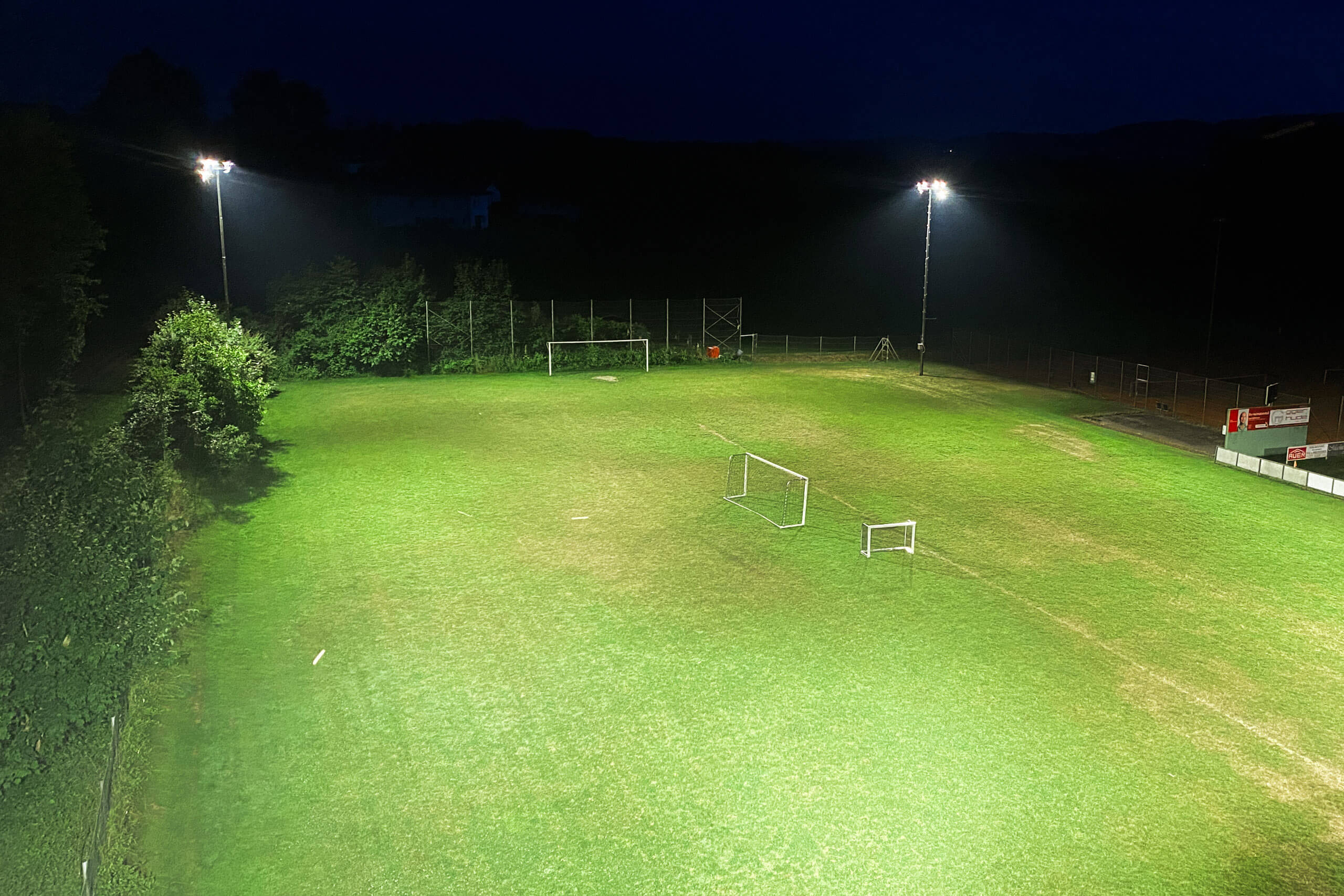 Beleuchtetes Fußballfeld bei Nacht von Illumina mit zwei Masten und leuchtenden Toren