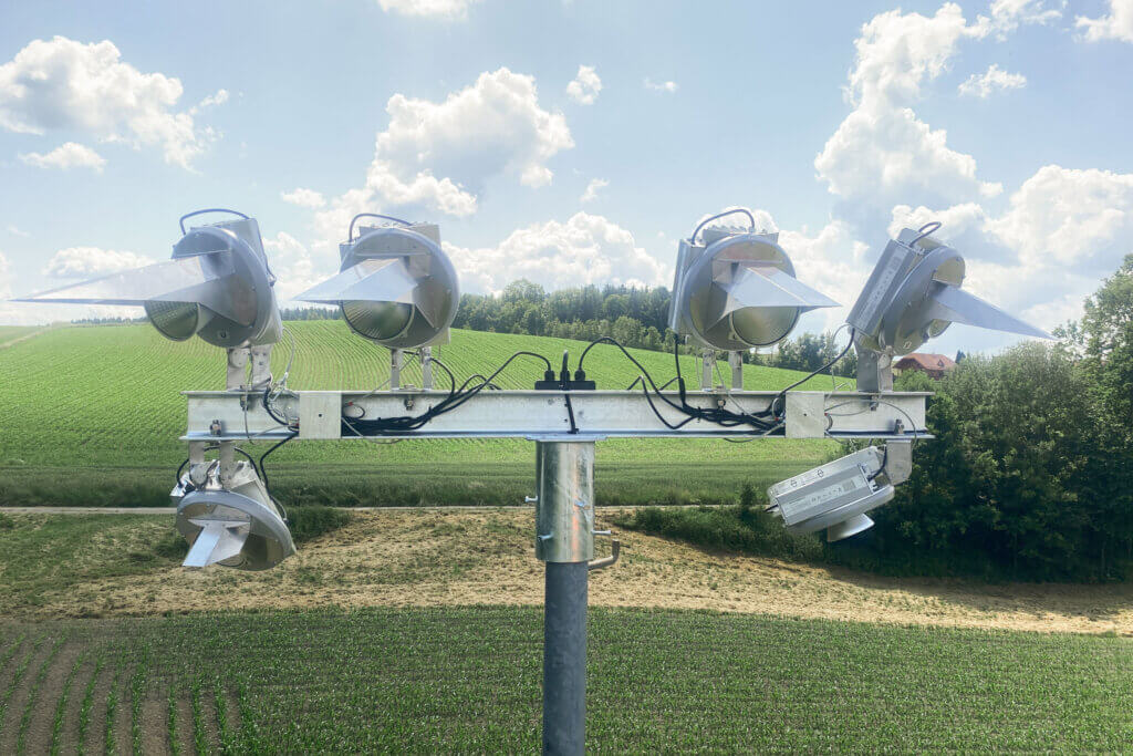Vier Scheinwerfer auf einem Mast in ländlicher Umgebung