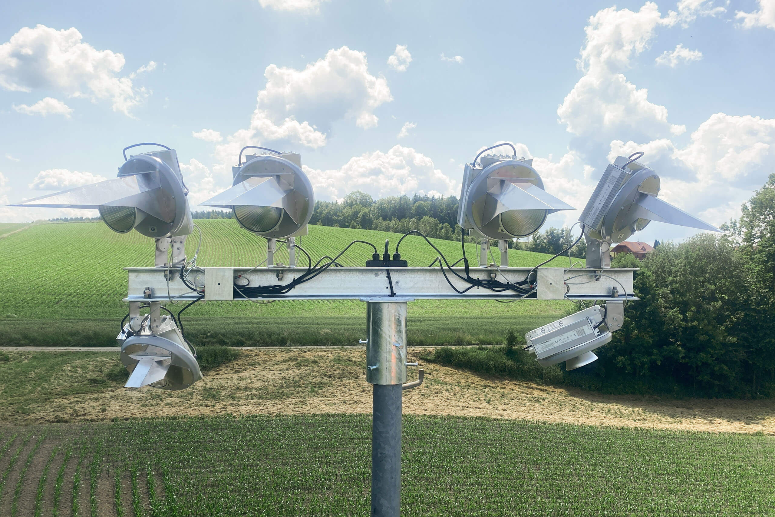 Vier Scheinwerfer auf einem Mast in ländlicher Umgebung