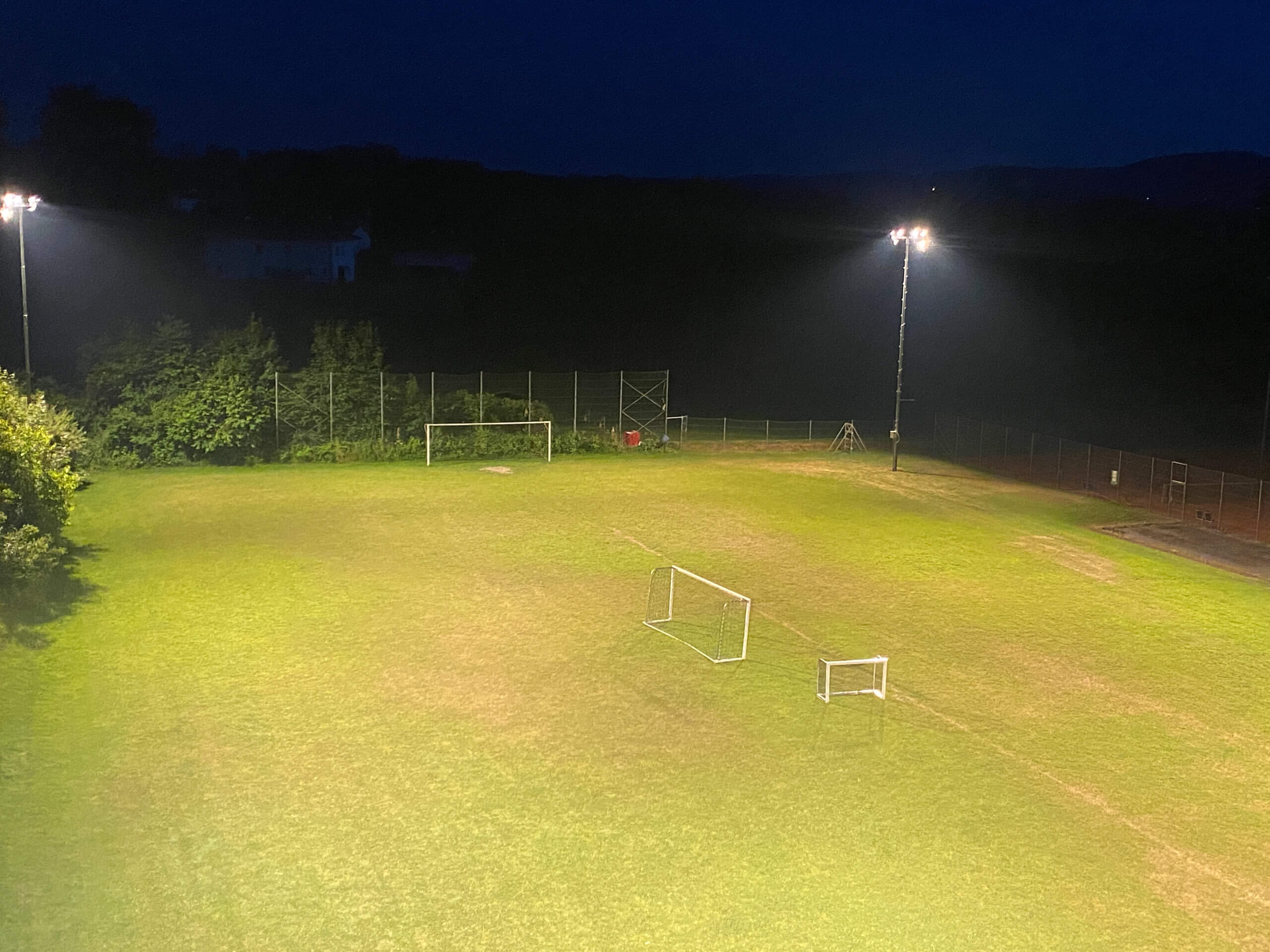 Fußballplatz mit Flutlichtbeleuchtung bei Nacht