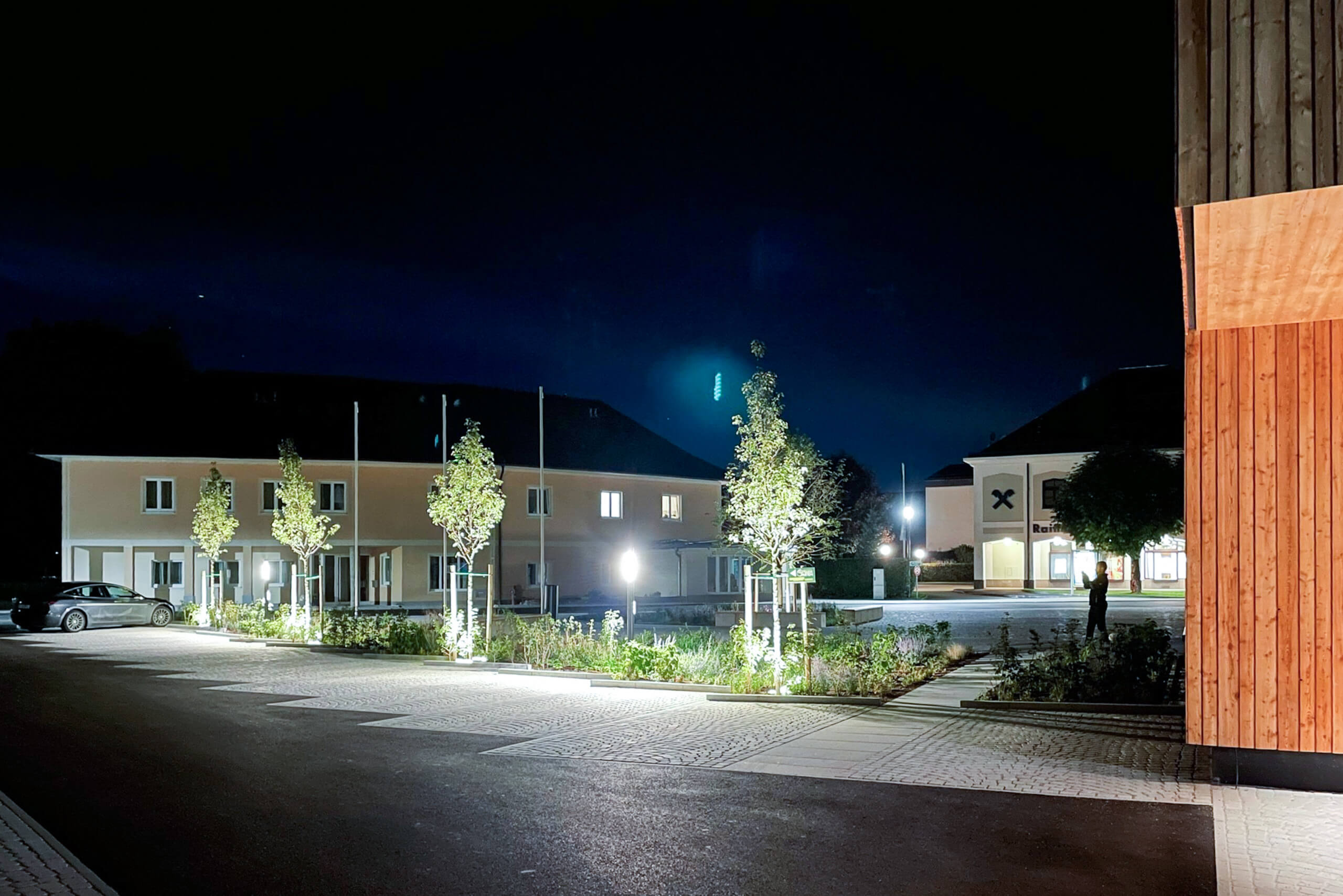 Beleuchtete Fassaden und Außenbereiche eines modernen Gebäudes bei Nacht