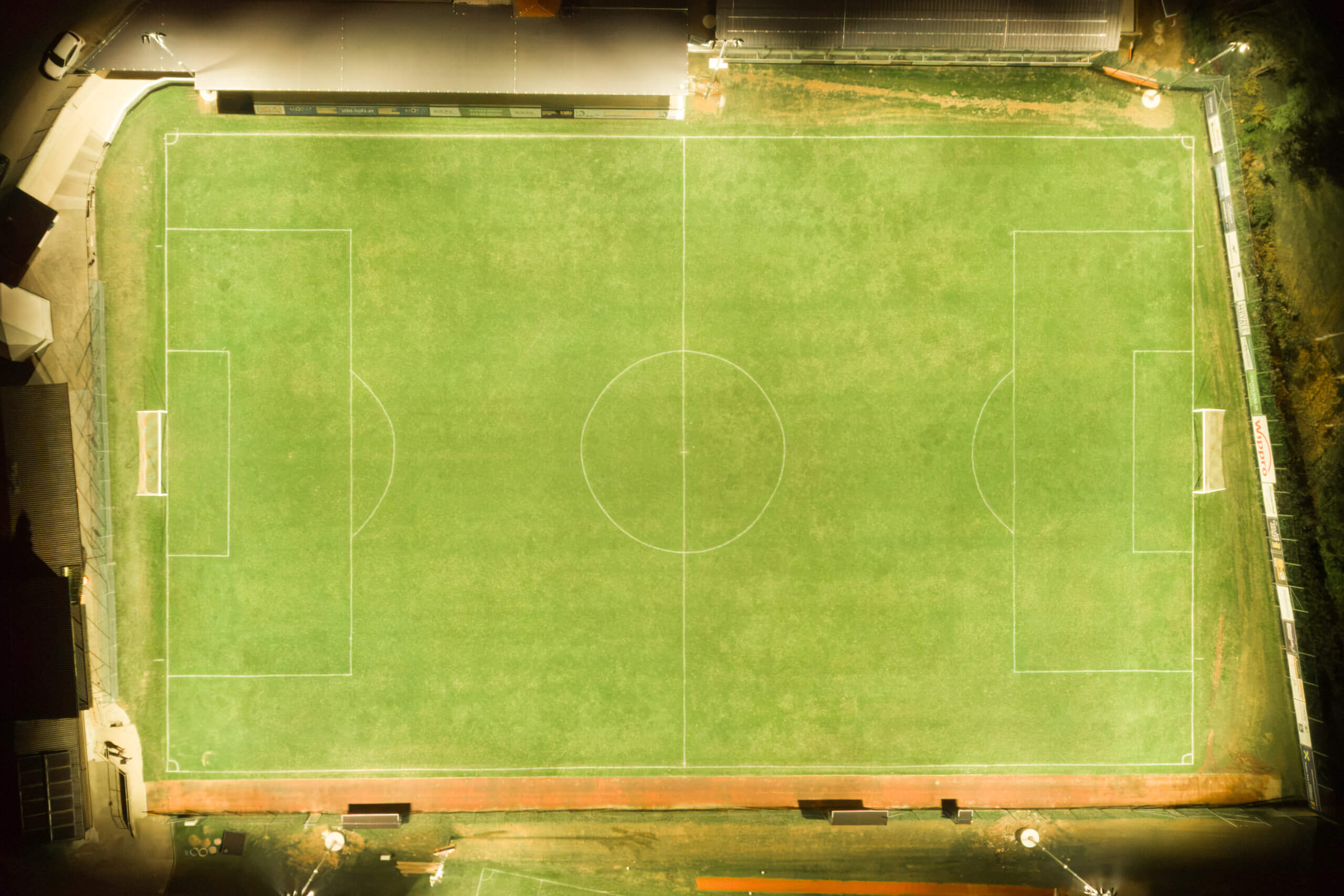 Beleuchteter Fußballplatz bei Nacht mit Spielfeldmarkierungen und Toren