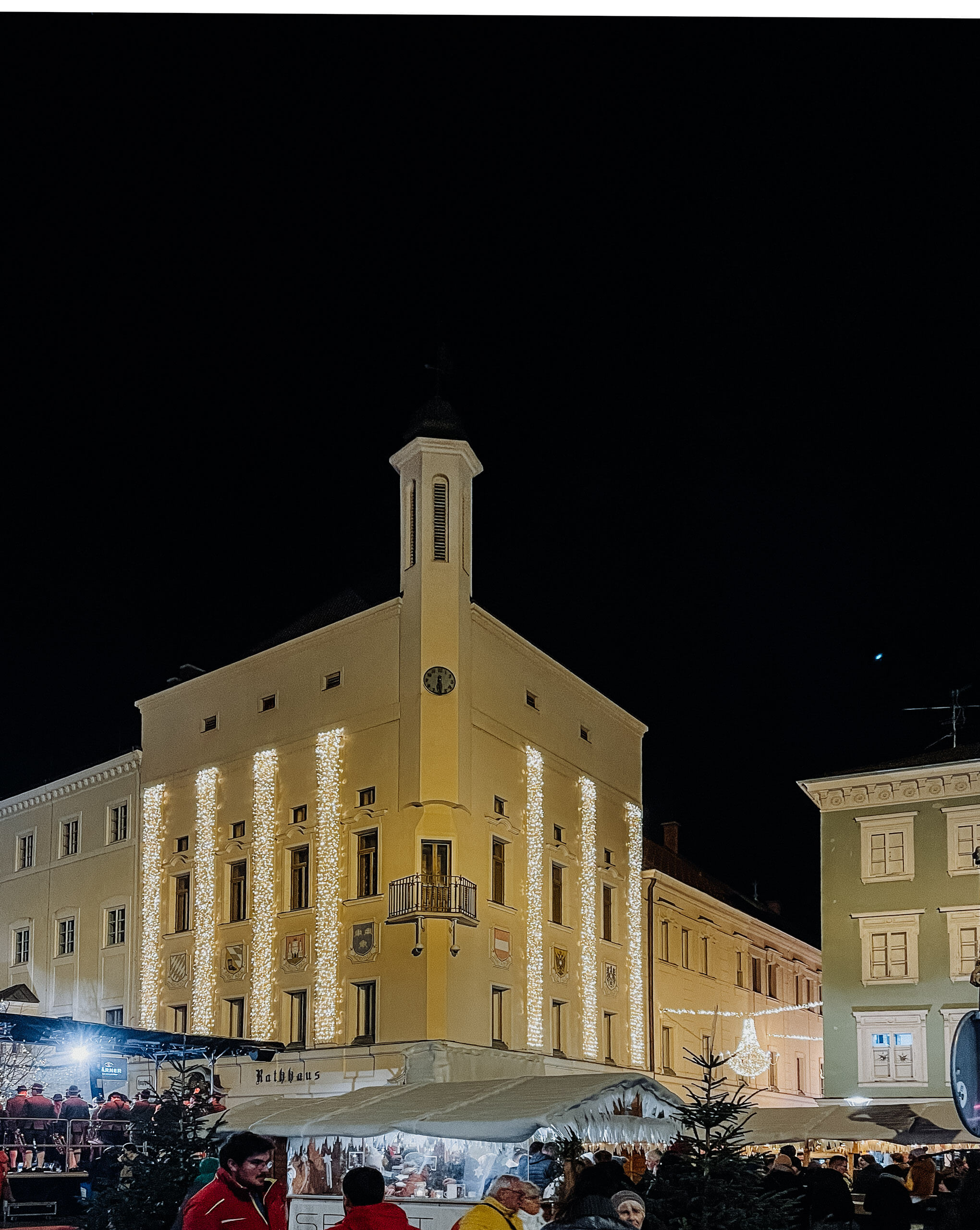 Weihnachtsbeleuchtung an einem Gebäude mit Marktständen.